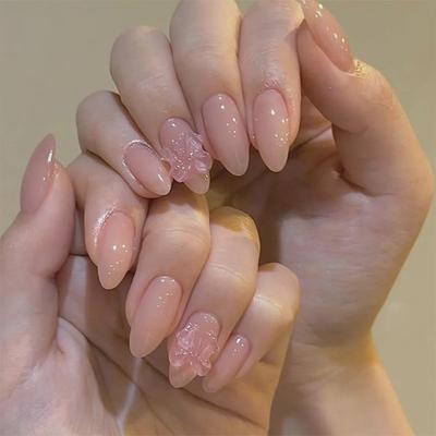 Luksusowe, różowe, sztuczne paznokcie z 3D diamentami i przezroczystym jak lód wzorem kokardki