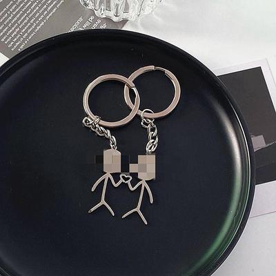 Nuotaikingas „Stickman“ širdies ir vidurinio piršto raktų pakabukas poroms – asmeninis mokyklinės rankinės priedas.
