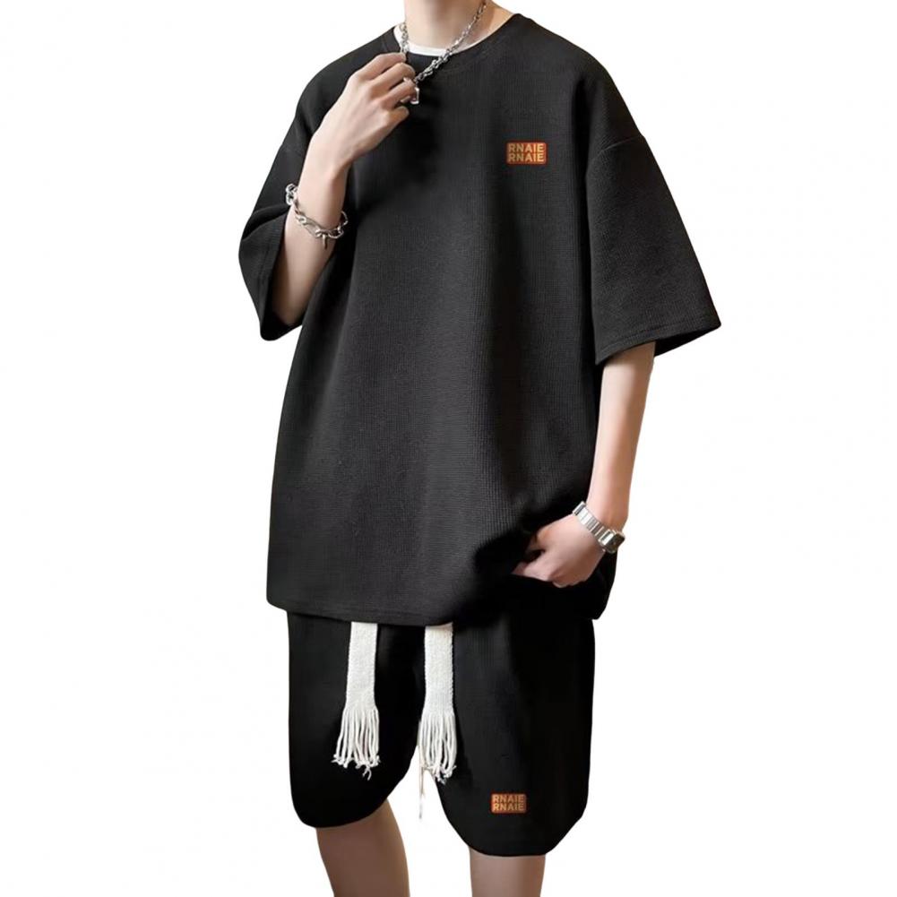 

2 шт./компл. Чоловічий літній повсякденний комплект Футболка з круглим вирізом та коротким рукавом Еластичний пояс на шнурку Широкі шорти Комплект з принтом літер Спортивний одяг 4XL чорний