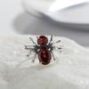 Pierścionek z pajęczym motywem w kolorze ciemnego wiatru, wykonany ze srebra próby 925, z naturalnym granatem i czarnym spinellem. Pierścionek damski, podkreślający indywidualność, w stylu tajskiego srebra.