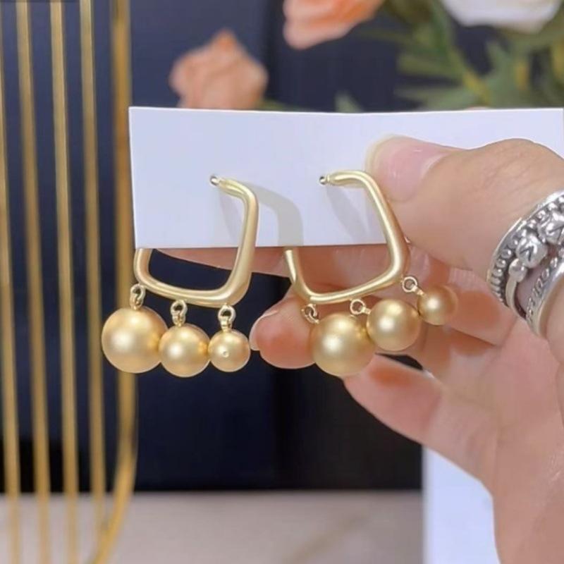 

Серьги-подвески в виде золотых матовых шариков, серьги с индивидуальным дизайном в стиле холодного ветра, нишевые серьги высокого класса.