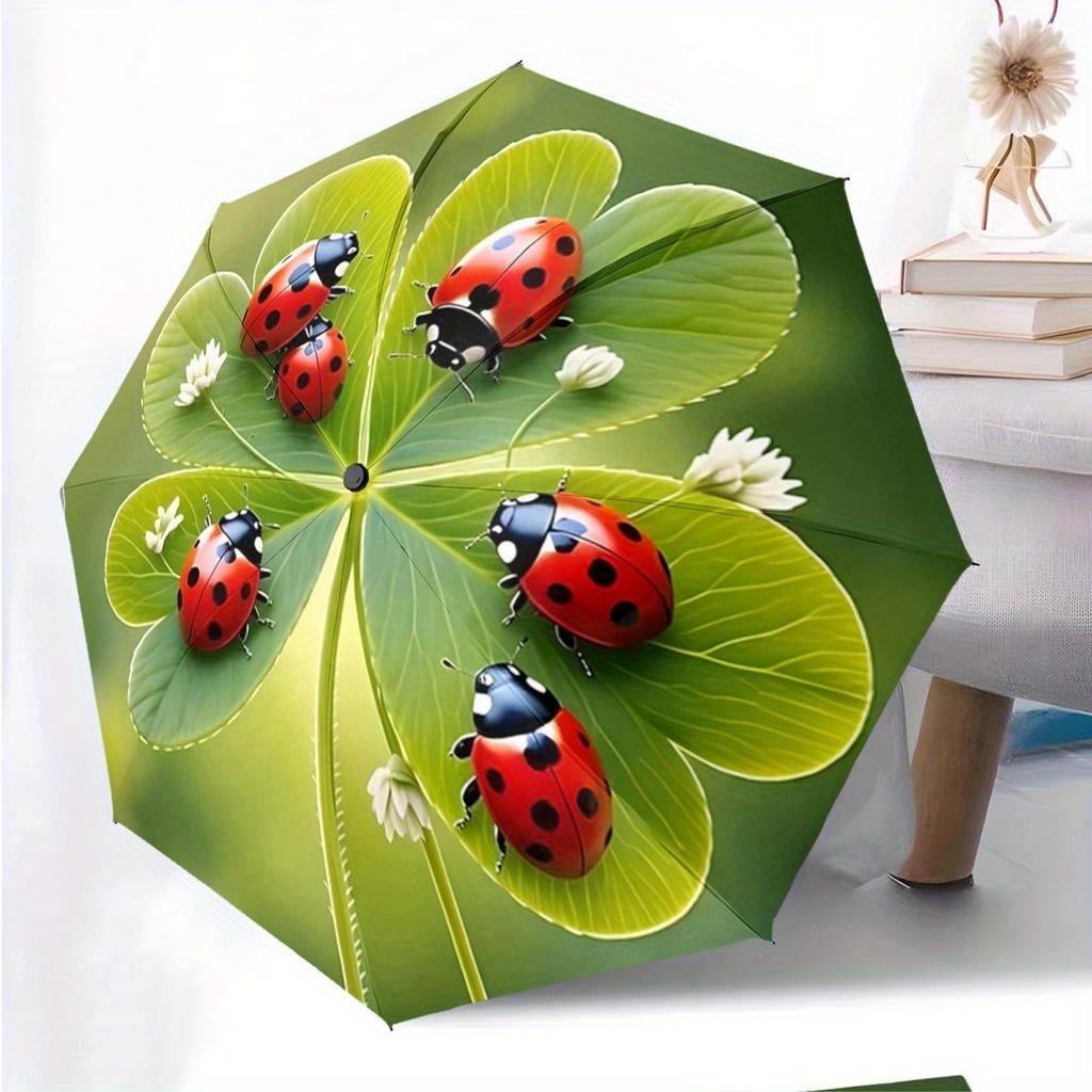 A Compact Folding Umbrella Featuring Ladybugs On a Backdrop of Green Leaves, Perfect for Gifting On Any Occasion.
