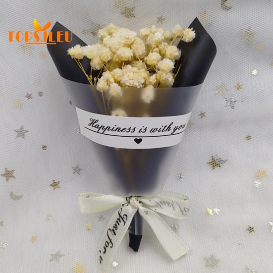 In Papier eingewickelte, mit getrockneten Blumen duftende Schleierkrautblüten, Schleife mit Buchstabenmuster, langanhaltende, lebendige Farbe, Blumenstrauß als Geschenk zum Valentinstag