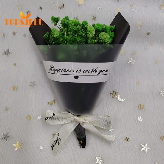 In Papier eingewickelte, mit getrockneten Blumen duftende Schleierkrautblüten, Schleife mit Buchstabenmuster, langanhaltende, lebendige Farbe, Blumenstrauß als Geschenk zum Valentinstag