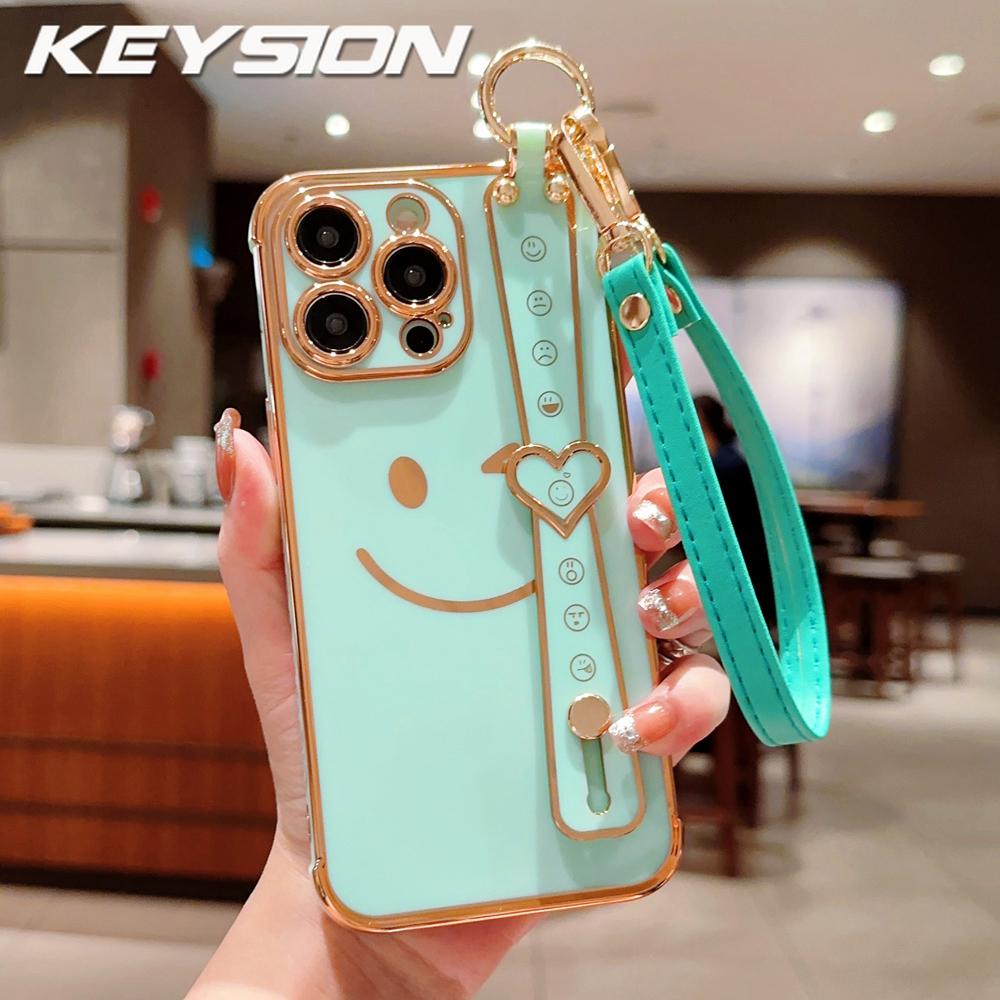 

KEYSION Чехол для телефона с ремешком на запястье и смайликом для iPhone 13 14 15 16 17 Pro Max 17 Air 16e 16 Plus с гальваническим покрытием, силиконовый шнурок, противоударная крышка for iPhone 17 мятный