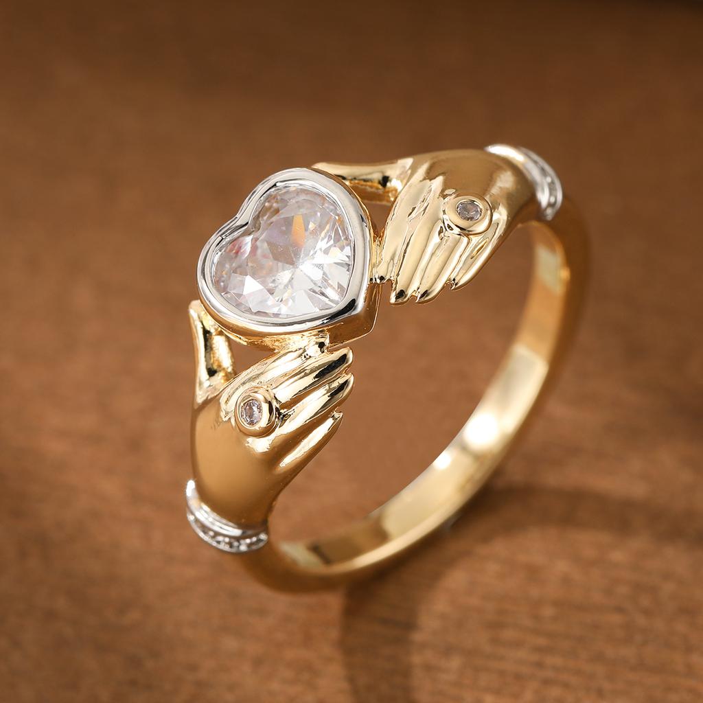 Luxurious hands holding a heart-shaped synthetic gemstone ring made of copper. Women's jewelry ring for a banquet.