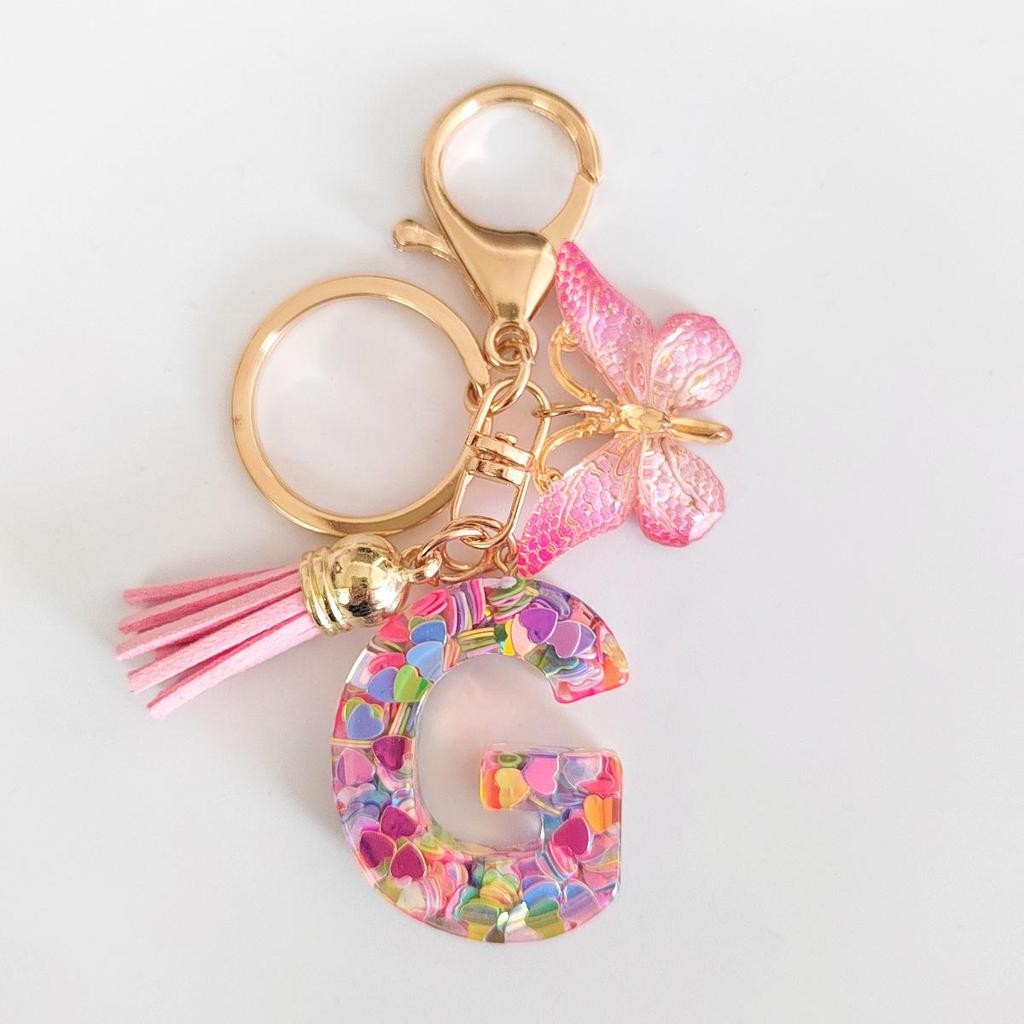 Rosa Glitzer Epoxidharz Schlüsselanhänger mit englischem Buchstaben und Schmetterlingsquaste