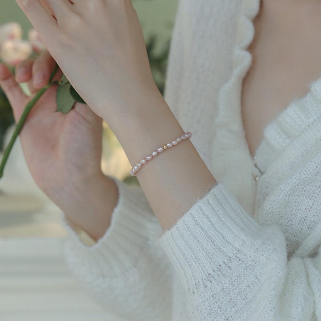 Super delicate, soft-toned orange, pink, and purple natural freshwater pearl bracelet with a small, bead-like design, elastic, and minimalist style