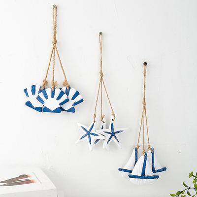 Rustikale Wanddekoration aus Holz im Küstenstil mit maritimen Strandmotiven, hängendem Ornament aus Juteseil, Seesternen, Meeresfischen und Segelboot – die perfekte Wanddekoration für Ihr Zimmer.