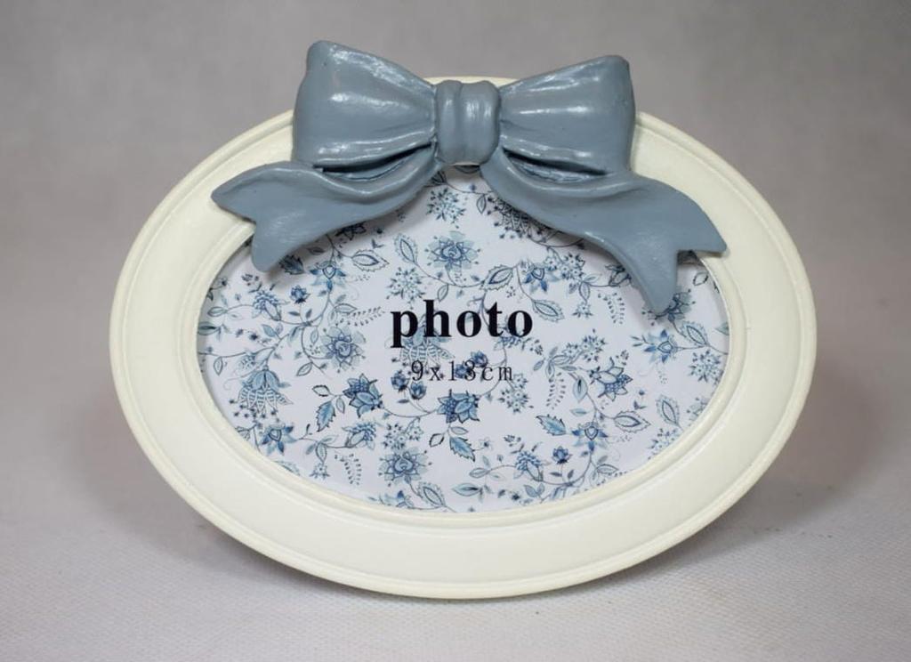 A charming white oval-shaped frame decorated with a bow
