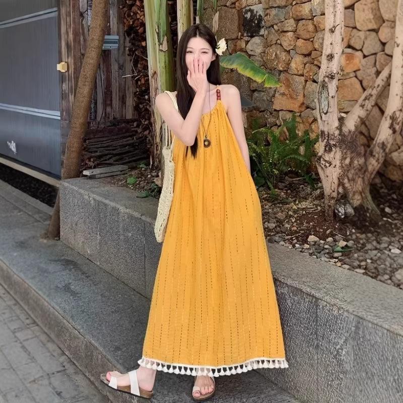 Beach vacation wind yellow fringed suspender dress women's summer 2026 new temperament loose A-shaped long skirt
