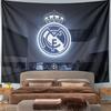 Illuminated Real Madrid crest with crown, displayed above a trophy setup. Patterned tapestry for bedroom and living room home decor