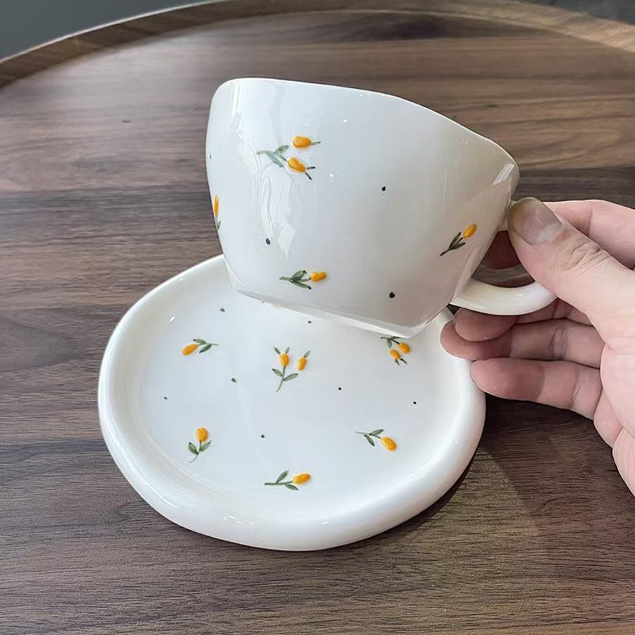 Ceramic coffee cup and saucer set, decorated with a small floral pattern.