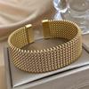 Bracciale alla moda in acciaio inossidabile intrecciato con un tocco dorato. Accessorio alla moda in versatile tonalità dorata.
