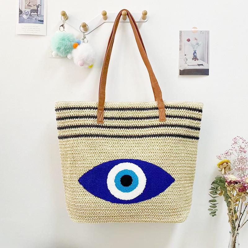 Umweltfreundliche Stroh-Schultertasche mit blauem Augen-Stickdesign für Sommerausflüge