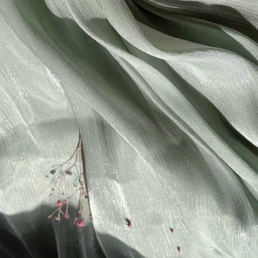 Soft shiny creased organza fabric with a smooth texture suitable for wedding dresses formal gowns and designer clothing fabrics