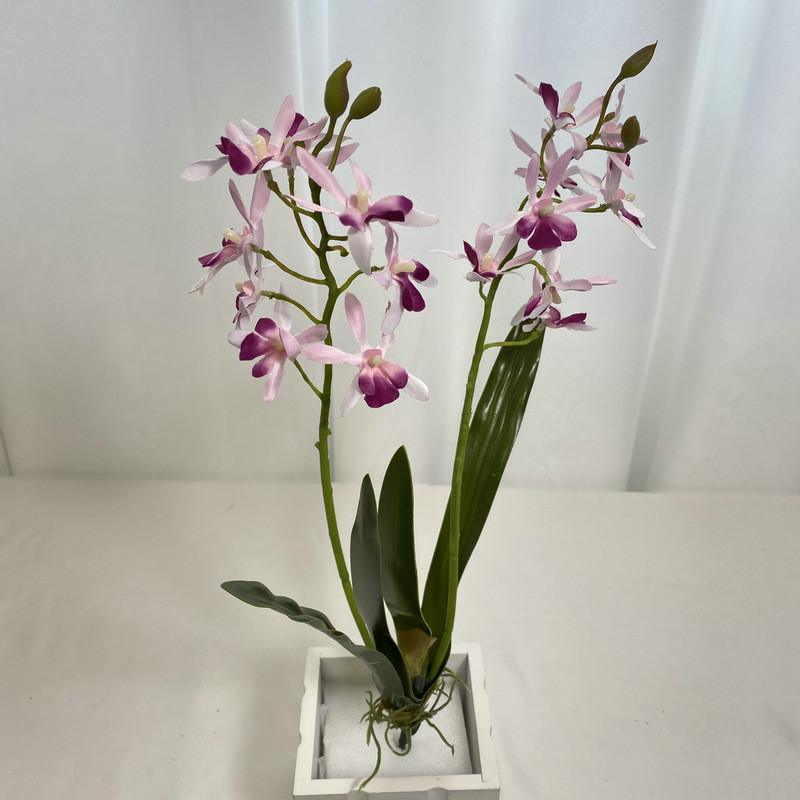 Realistische Seiden-Dendrobium-Orchidee mit Blättern für Blumengesteck auf dem Esstisch